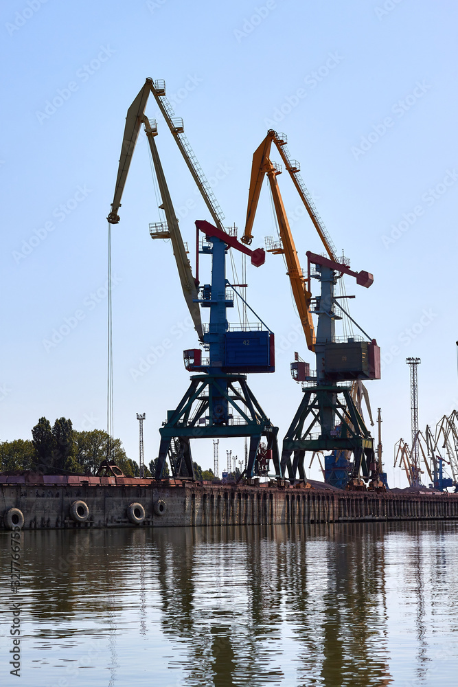 Cranes in cargo port translating coal. Industrial scene. Big port-cranes. Danube river