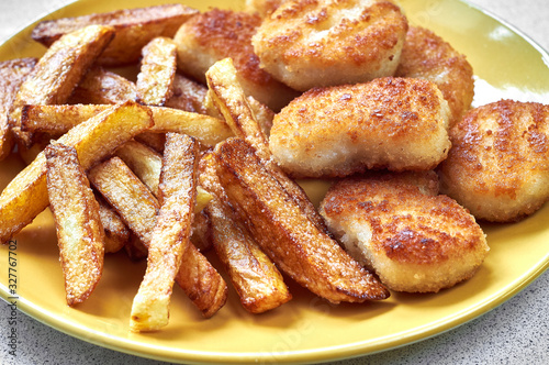 Tasty homemade potato french fries with chiken nuggets on yellow dish