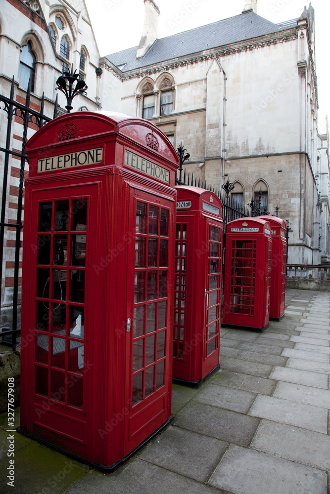 a line of four old red British telephone boxes in London, England.