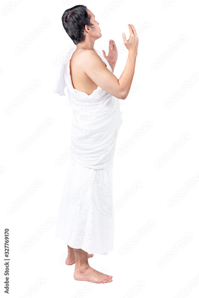 Asian Muslim man in ihram clothes standing and praying while raised arms Asian Muslim man in ihram clothes standing and praying while raised arms