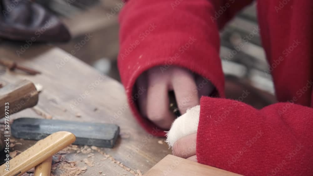 The guy sharpens a chisel for cutting wood on a grindstone manually. Close-up