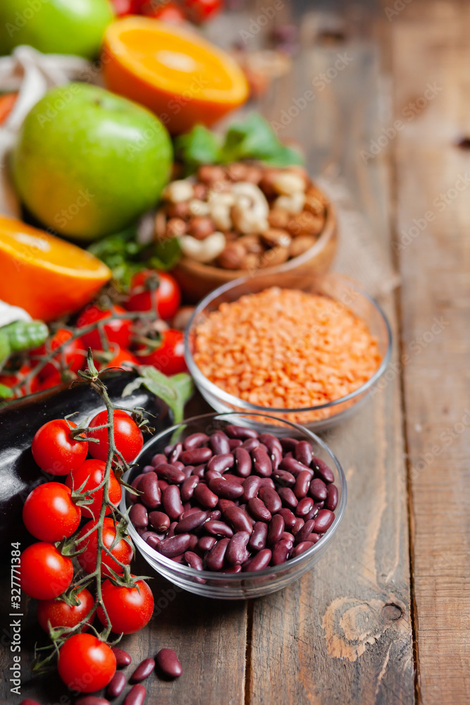 Concept of healthy vegan food, clean eating. Fresh raw ingredients on wooden background: vegetables, fruits, nuts, beans and lentils. No plastic, eco-friendly shopping for zero waste. Copy space