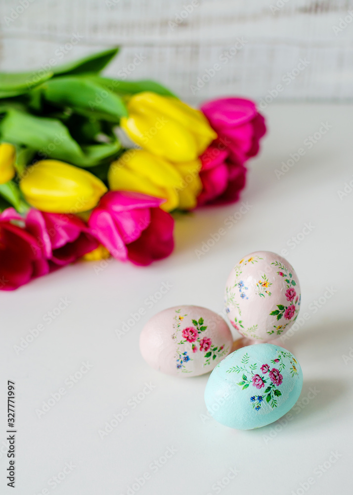 Easter card. Pink and yellow tulips and colored eggs on a white wooden background. Rustic style.