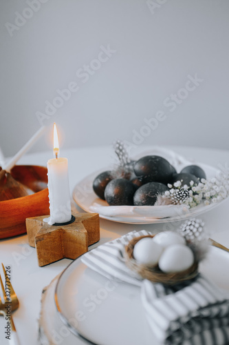 Easter table setting with white plate  gray textile napkin  candles  quail and chicken eggs and blossom branch.Mock up easter card