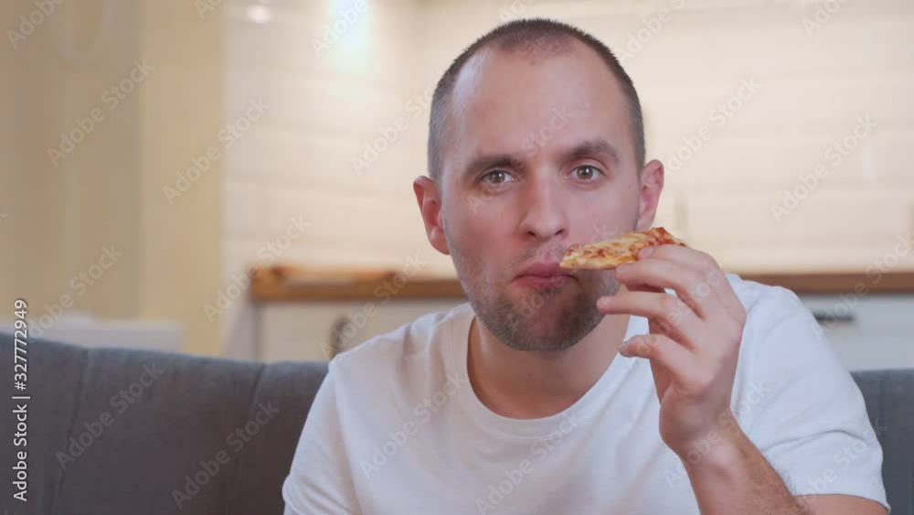 Portrait man eating pizza, watching favorite comedy on tv while relaxing at sofa in the living room. Portrait man eating pizza, watching favorite comedy on tv while relaxing at sofa in the living room.