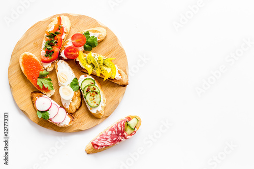 Set of bruschetta on cutting board on white background top-down copy space