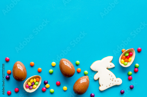 Sweet Easter symbols - chocolate eggs and bunny gingerbread - on blue background top-down frame copy space
