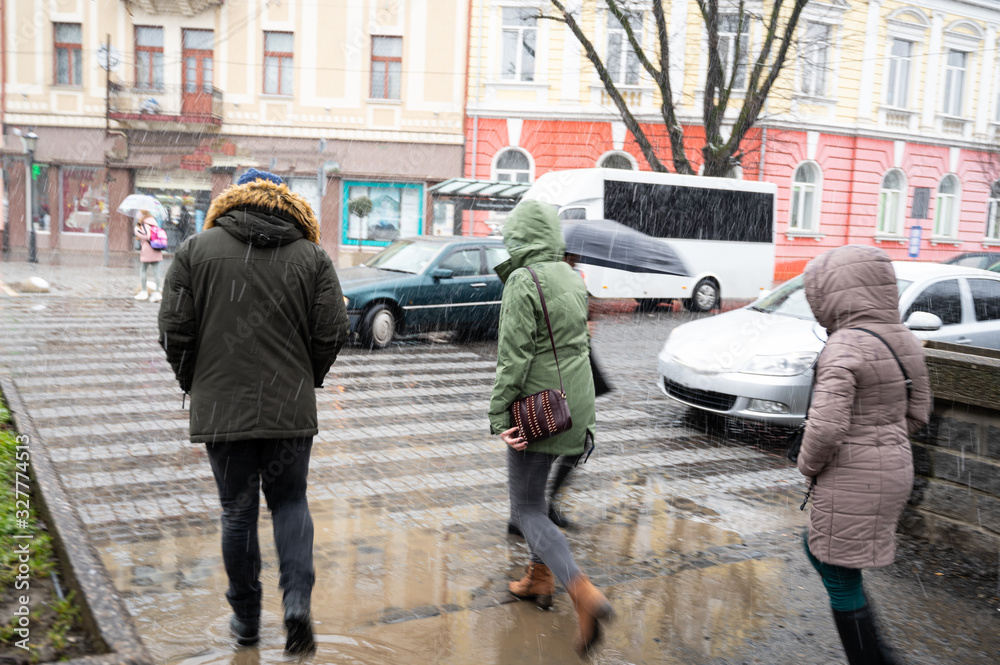 Busy city street people on zebra crossing in a rainy day. Dangerous situation. Defocused image