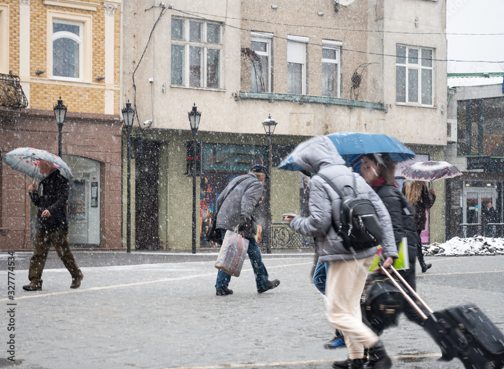 People with umbrella walking down the street on rainy day. Intentional motion blur