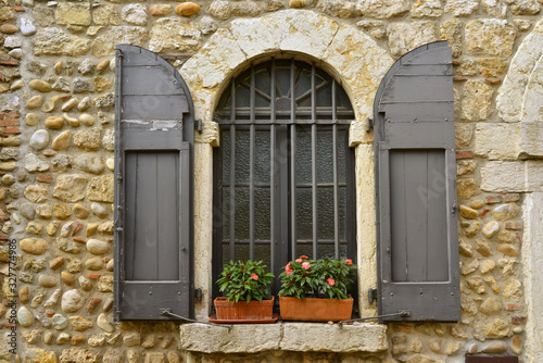 Fenêtre à barreaux et volets bois sur vieux mur en pierres à Pérouges (01800), département de l'Ain en région Auvergne-Rhône-Alpes, France