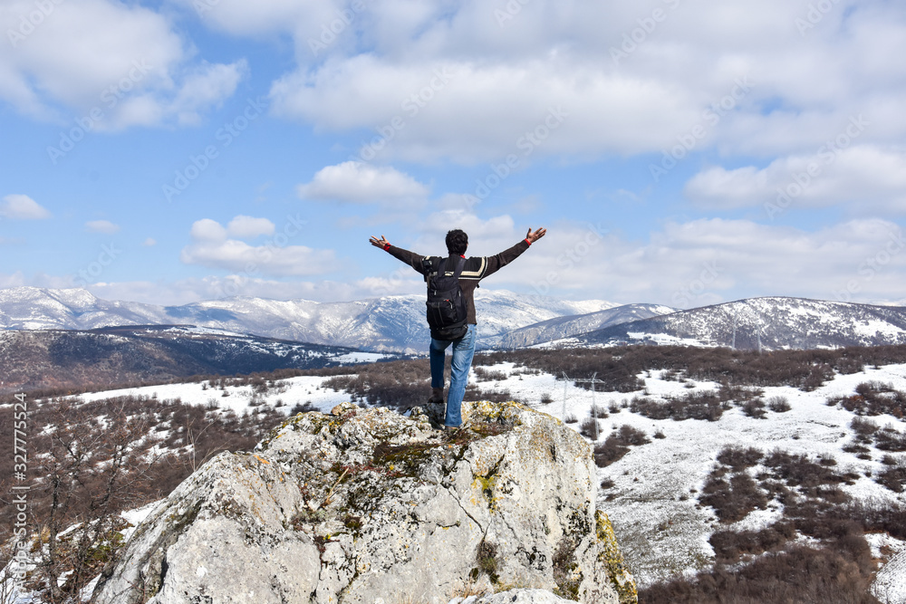 Obraz premium Tourist man is feeling free and standing with hands up on the top of the mountain. Climber enjoy in mountains in spring. Beautiful landscape