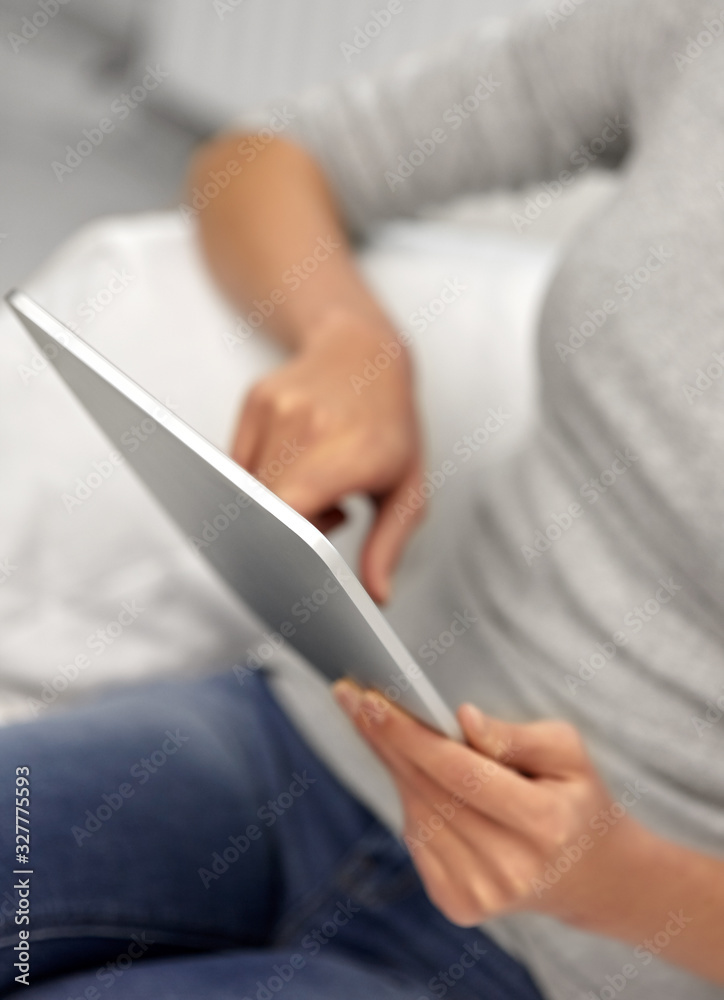 technology, leisure and people concept - close up of woman with tablet pc computer sitting on sofa at home