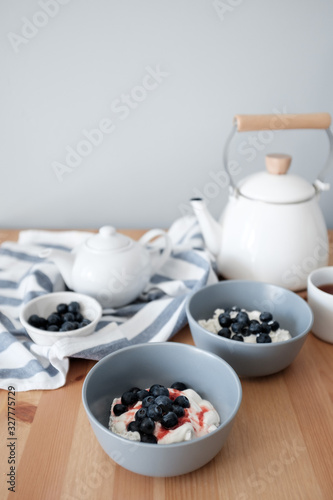 Tasty breakfast of Tvorog, farmers cheese, curd cheese or cottage cheese and blueberries in gray bowls. 