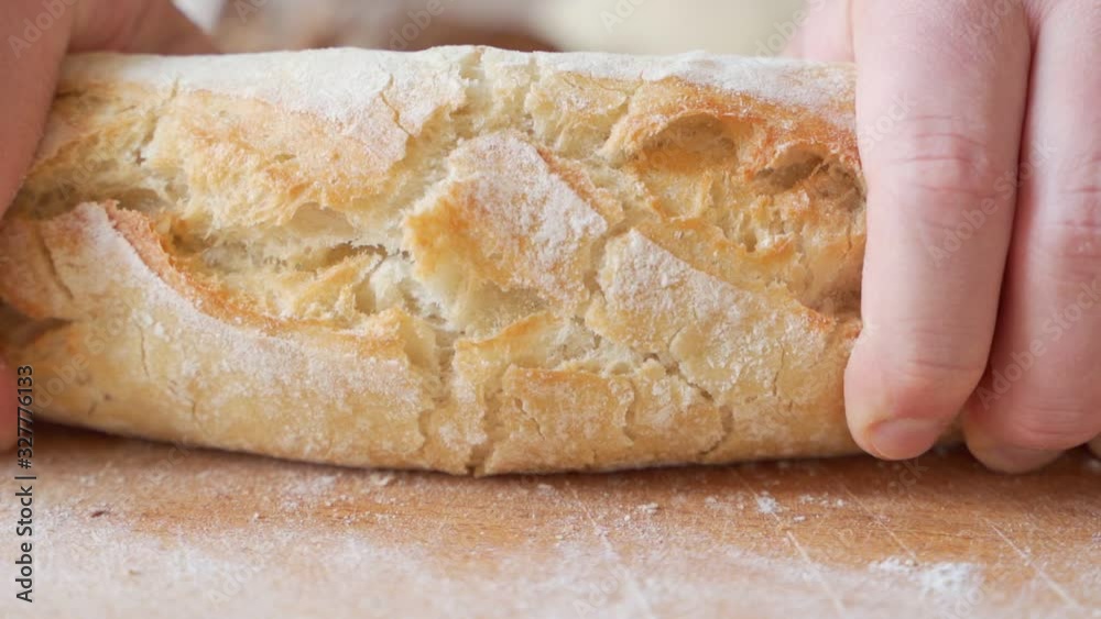 Slow motion of hands breaking a freshly baked loaf of bread