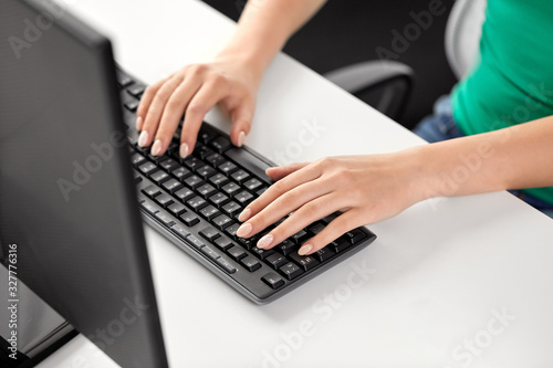 technology and people concept - female hands with manicure typing on computer keyboard on table