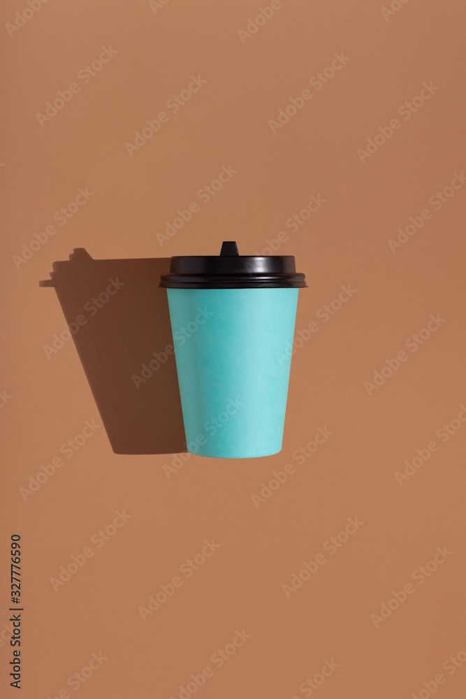 Brown background with one paper blue cup. Trend hard shadow. Place for your text. Brown background with one paper blue cup. Trend hard shadow. Place for your text.