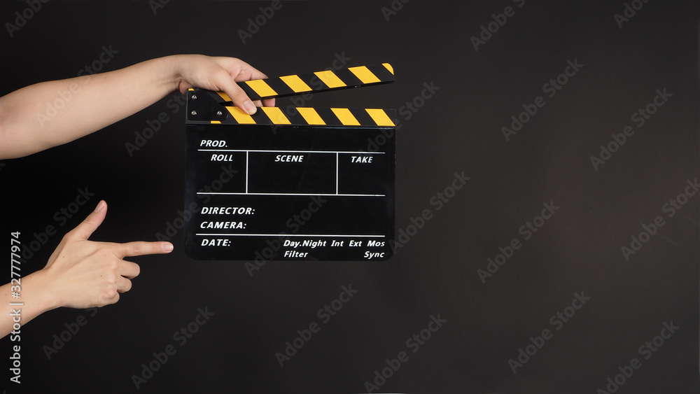 Two Hand's holding yellow&black Clapperboard or movie slate use in video production and cinema industry on black background.