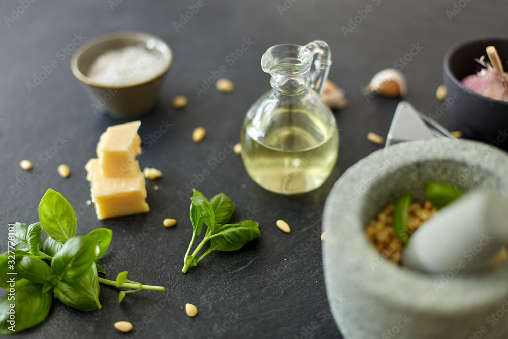 food cooking and culinary concept - parmesan cheese, pine nuts, vinegar and garlic for basil pesto sauce making on stone table food cooking and culinary concept - parmesan cheese, pine nuts, vinegar and garlic for basil pesto sauce making on stone table