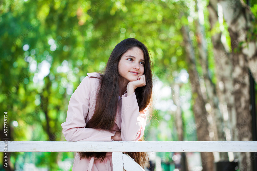 Portrait of a young brunette girl in pink coat on a background of autumn park Portrait of a young brunette girl in pink coat on a background of autumn park