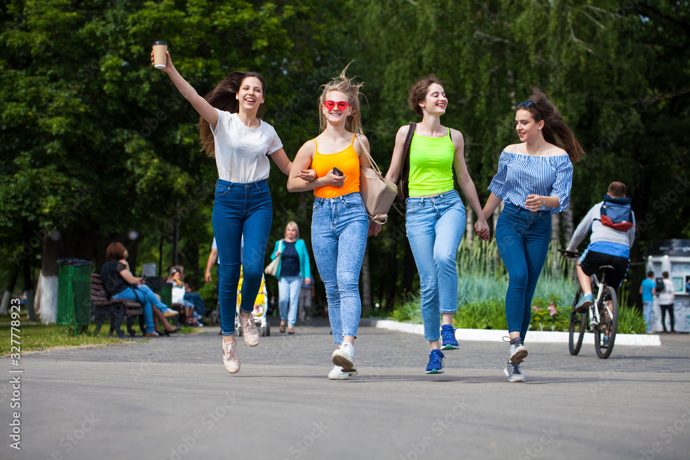 Happy women in blue jeans walking in summer park Happy women in blue jeans walking in summer park
