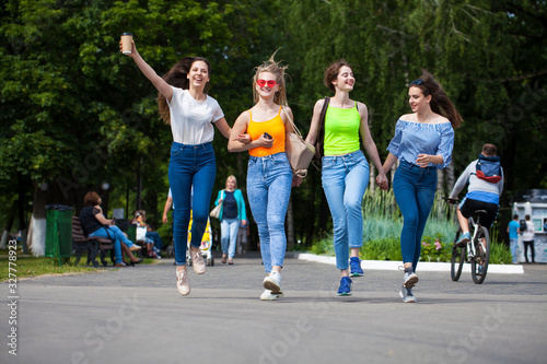 Fototapeta Naklejka Na Ścianę i Meble -  Happy women in blue jeans walking in summer park