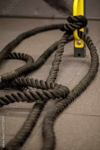 Black crossfit or battle rope. Rolled climbing gym exercise rope on the floor.