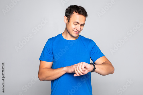 Photo of stylish handsome young sportsman using smart watch isolated on white background.