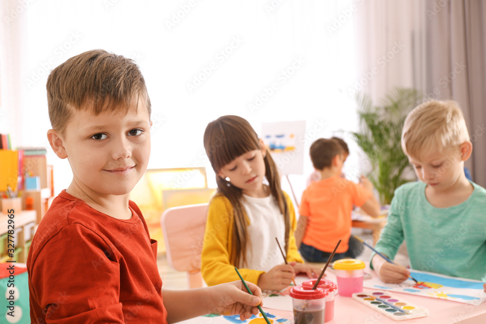Cute little children painting at table in room Cute little children painting at table in room