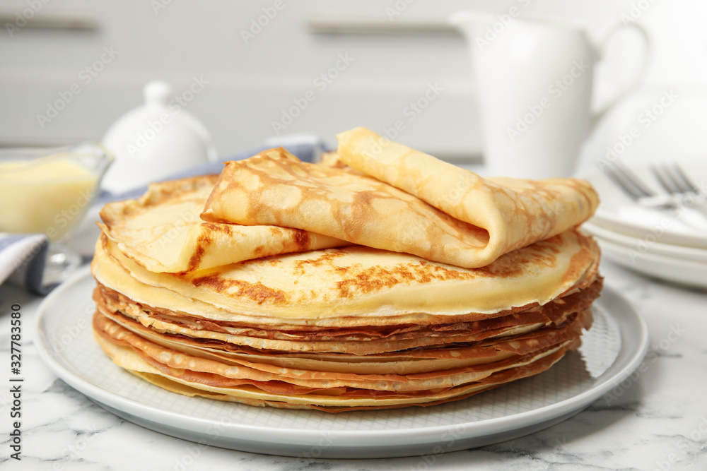 Stack of fresh thin pancakes on white marble table Stack of fresh thin pancakes on white marble table
