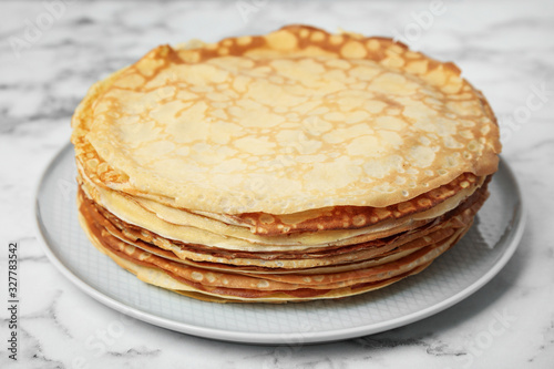 Stack of fresh thin pancakes on white marble table