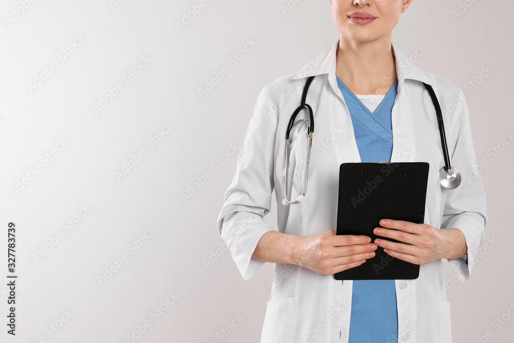 Doctor with stethoscope and clipboard on light grey background, closeup. Space for text Doctor with stethoscope and clipboard on light grey background, closeup. Space for text