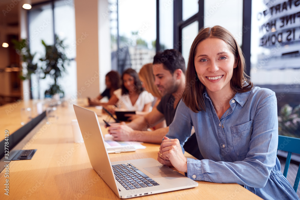 Portrait Of Businesswoman Working At Desk In Shared Open Plan Office Workspace Portrait Of Businesswoman Working At Desk In Shared Open Plan Office Workspace