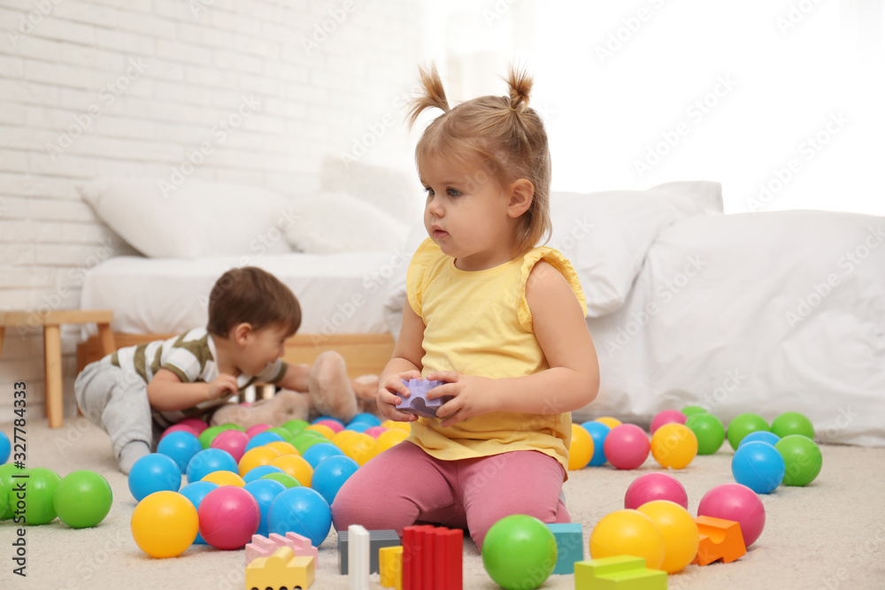 Cute little children playing with toys on floor at home Cute little children playing with toys on floor at home