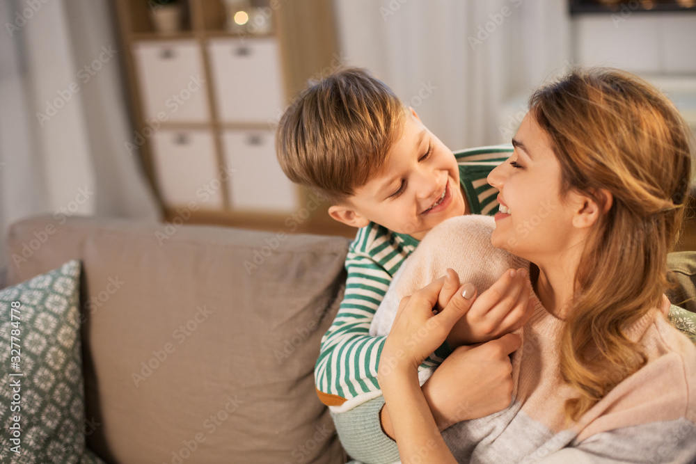 family, love and people concept - happy smiling mother and son hugging at home in evening family, love and people concept - happy smiling mother and son hugging at home in evening
