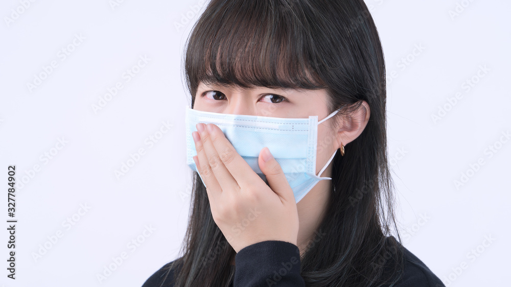 Woman coughing with mask - young Asian covering the mouth, feeling unwell with wearing medical blue face mask isolated on white background, close up. Woman coughing with mask - young Asian covering the mouth, feeling unwell with wearing medical blue face mask isolated on white background, close up.