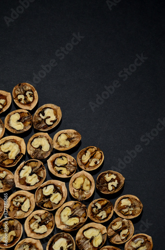 walnut halves in the lower left corner on a dark background top view vertical orientation © Svetlana
