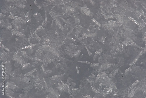 Close up sunlit ice carpet from sparkling and flaring sharp large crystals of snow and ice