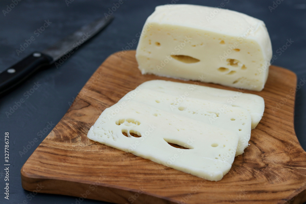 Suluguni Georgian cheese sliced on a wooden board against a dark background