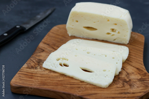 Suluguni Georgian cheese sliced on a wooden board against a dark background