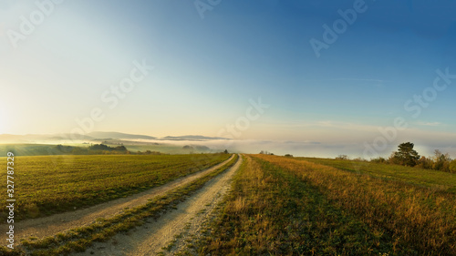 Povazsky Inovec Hill in Slovakia in the valley on sunrise. Landscape photo of field with green grass  fog and beautiful sun rays. Perfect view point from meadow on sunrise. Slovakia landscape.
