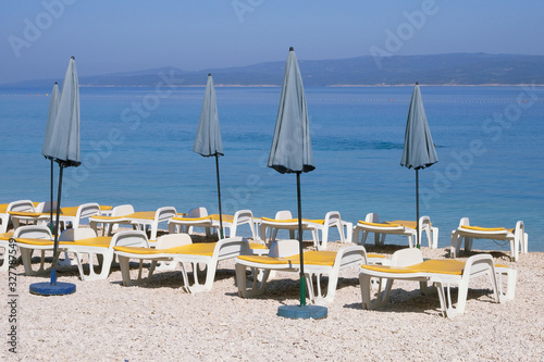 Blue umbrellas and loungers for relax and comfort on sea beach. Happy summer vacations and  tourism concept. Paid service on beaches.