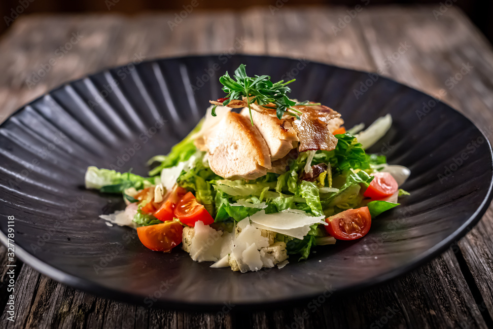 Caesar salad with fresh vegetables and crispy chicken on wooden background Caesar salad with fresh vegetables and crispy chicken on wooden background