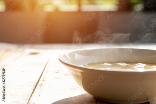 Photography Tom Yum or Mushroom Soup, which has hot steam in a bowl, placed on a table in th