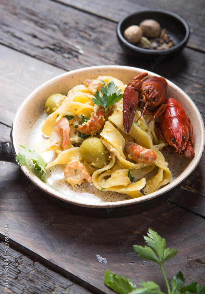 Seafood fettuccine pasta with crayfishes, octopus shrimps, on stone pan. Gourmet dish