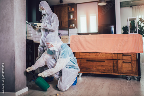 Specialists in protective suits do disinfection or pest control in the apartment. photo