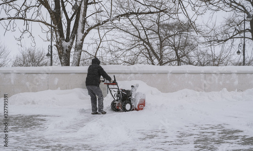 Man with a snow blower removing snow at street. © Vladimir Arndt