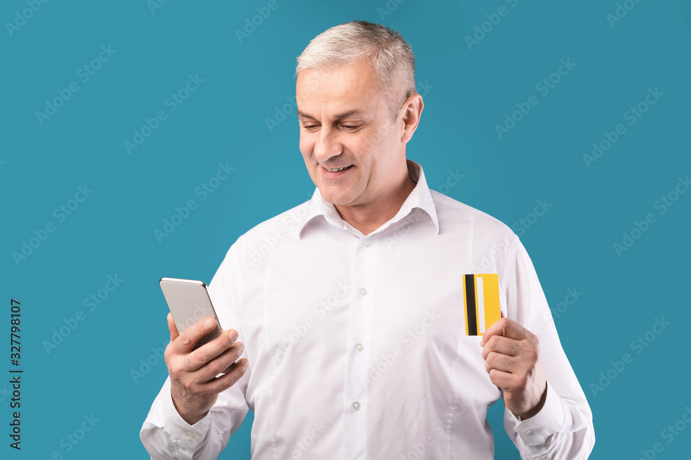 Happy mature man holding debit card and mobile phone Happy mature man holding debit card and mobile phone