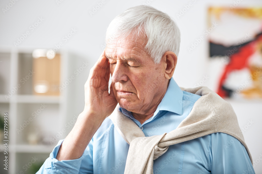 Exhausted senior white-haired man with closed eyes touching temple while feeling headache Exhausted senior white-haired man with closed eyes touching temple while feeling headache