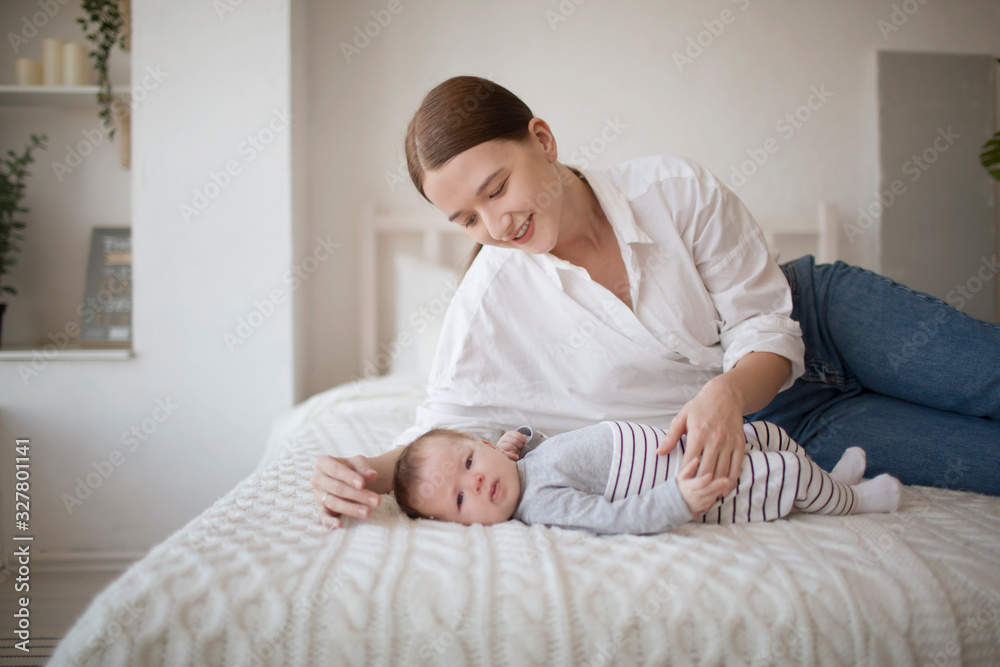 Happy mother and baby child lying on bed together Happy mother and baby child lying on bed together