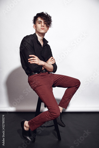 Young guy in a black shirt similar to Adriano Celentano posing on a white background. Fashion portrait photo